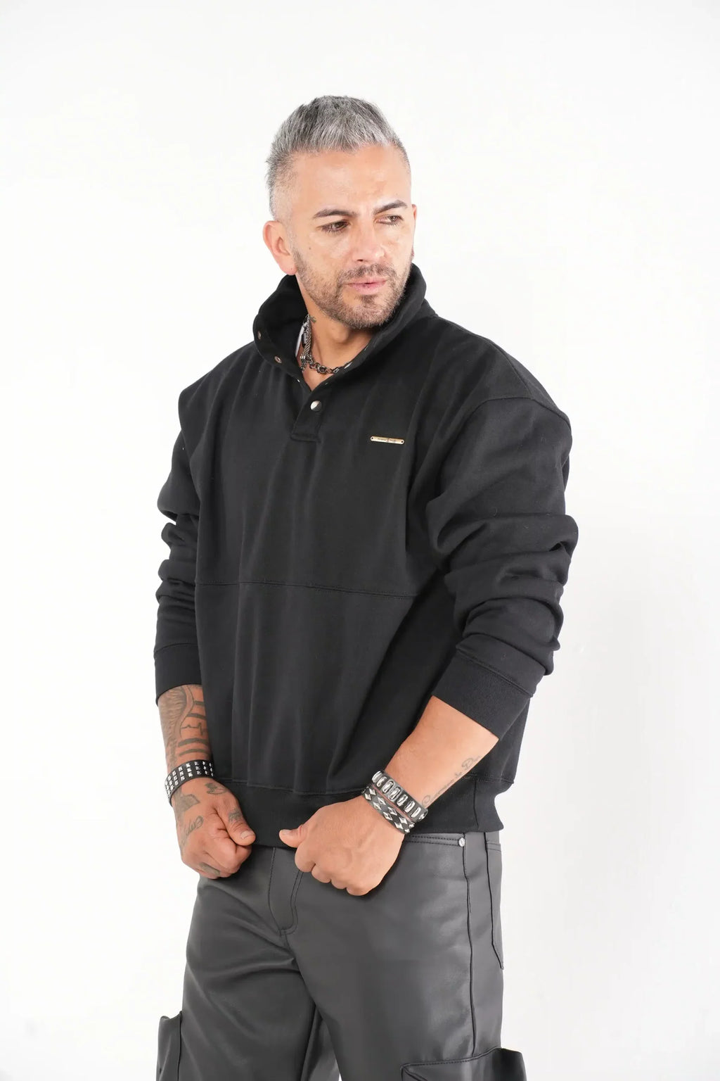 Buzo tipo sudadera negra con cuello alto y broches metálicos