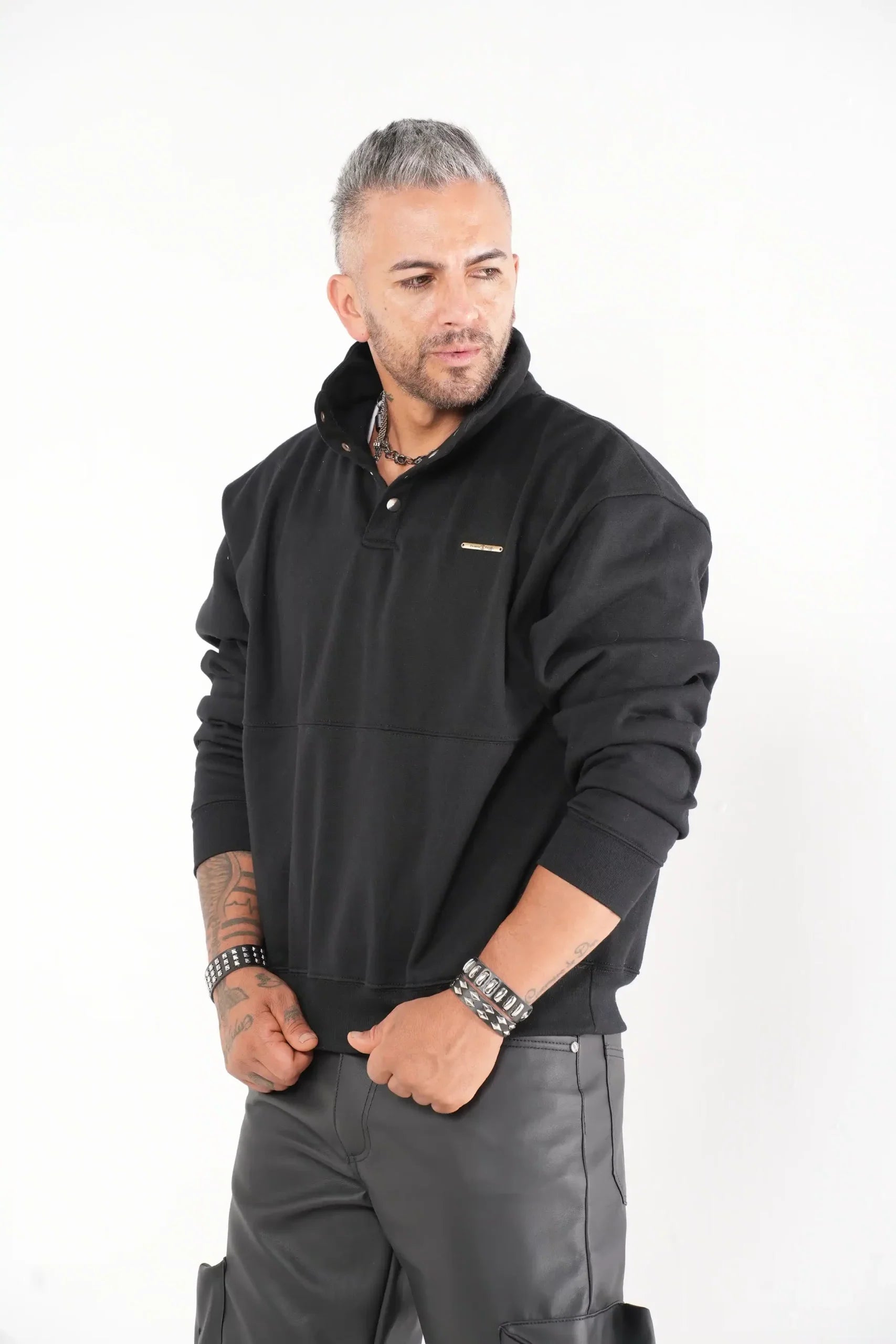 Buzo tipo sudadera negra con cuello alto y broches metálicos