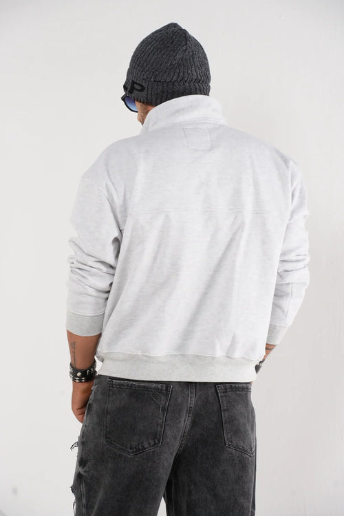 Buzo tipo sudadera gris claro con cuello alto y broches metálicos