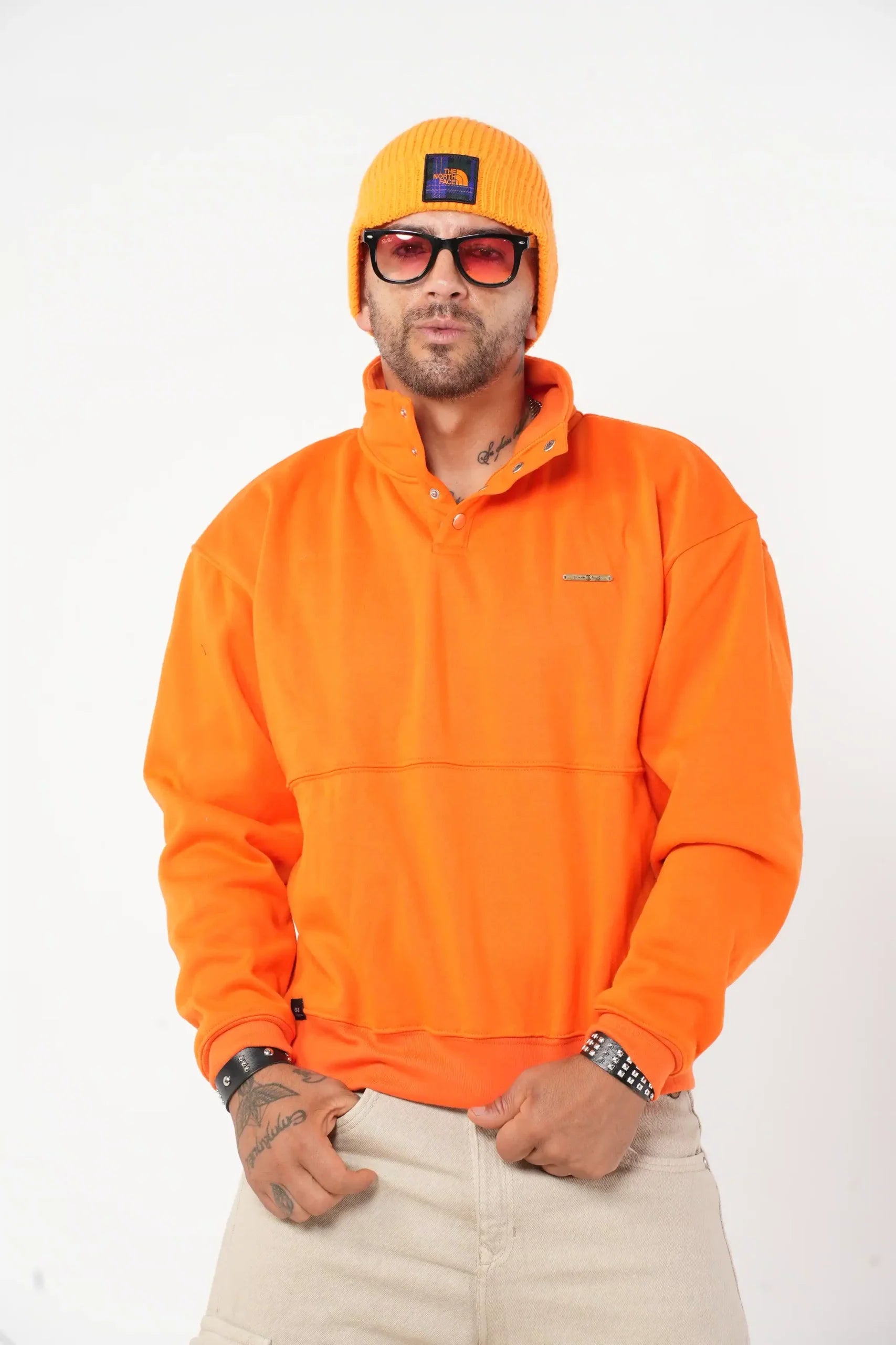 Buzo tipo sudadera naranja con cuello alto y broches metálicos